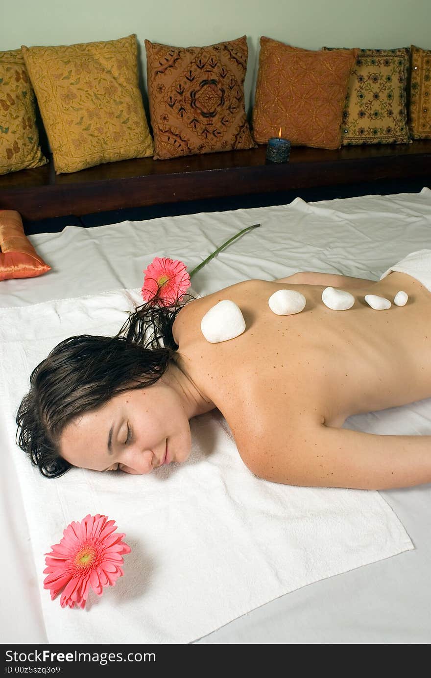 Woman closes her eyes and relaxes as she gets a hot stone massage. Vertically framed photograph. Woman closes her eyes and relaxes as she gets a hot stone massage. Vertically framed photograph.