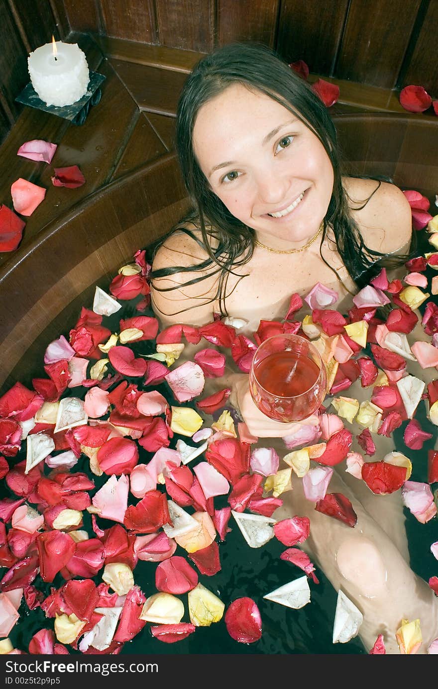 Woman smiling as she soaks with flower petals in a tub. Vertically framed photograph. Woman smiling as she soaks with flower petals in a tub. Vertically framed photograph.