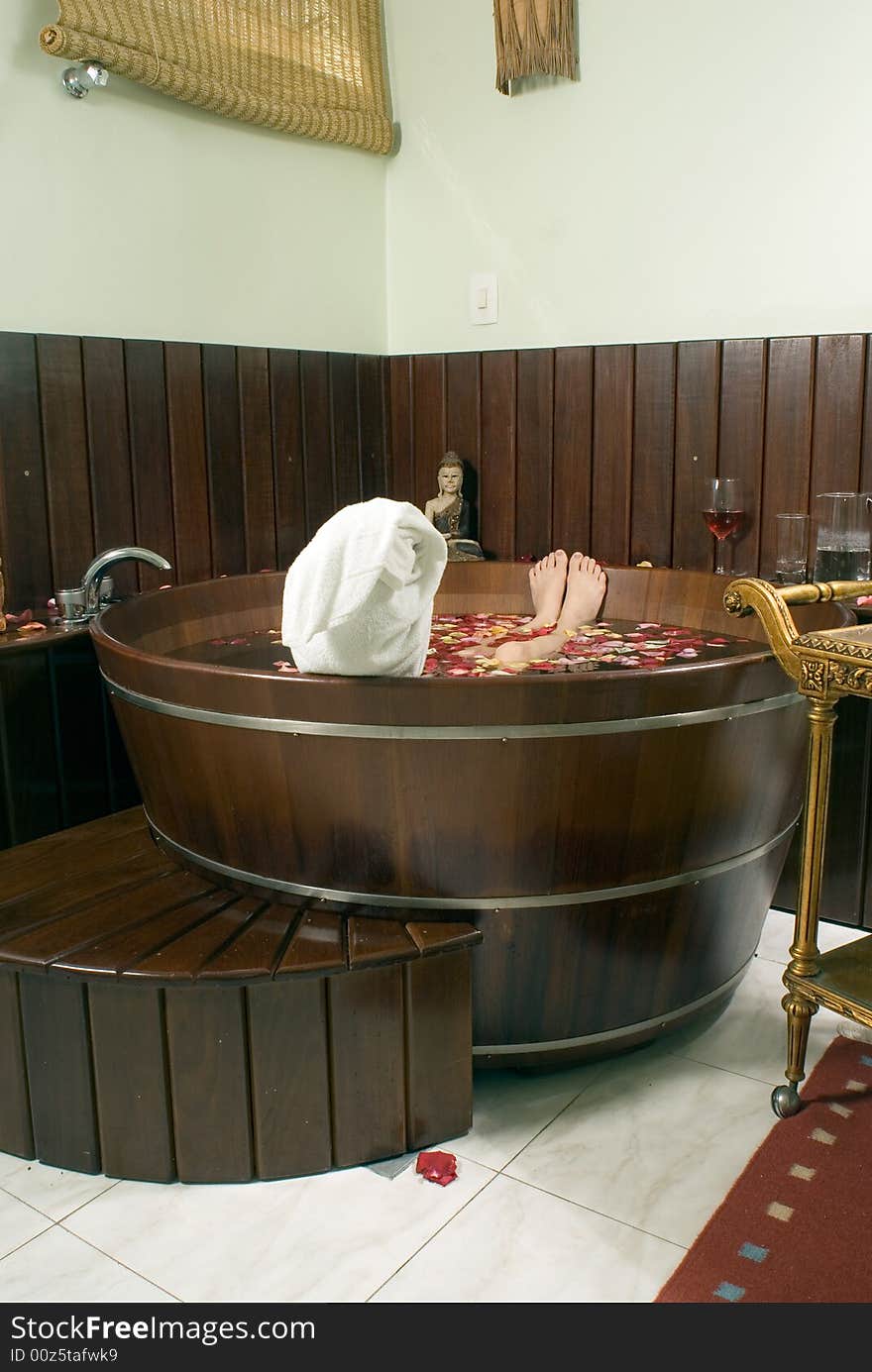 Picture of the back of a woman's head soaking in a tub filled with flower petals. Vertically framed photograph. Picture of the back of a woman's head soaking in a tub filled with flower petals. Vertically framed photograph