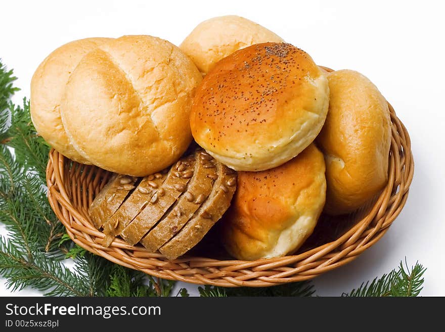 Basket full of fresh rolls and bread; pine needles as a background