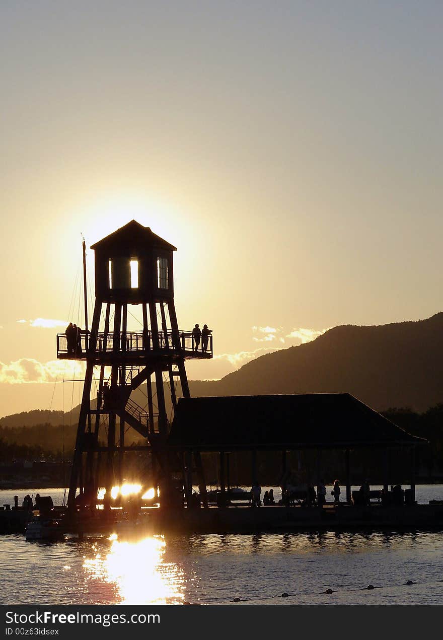 Observation tower in silhouette at sunset on Memphremagog lake, province of Quebec, Canada, with Mont-Orford in background. Observation tower in silhouette at sunset on Memphremagog lake, province of Quebec, Canada, with Mont-Orford in background