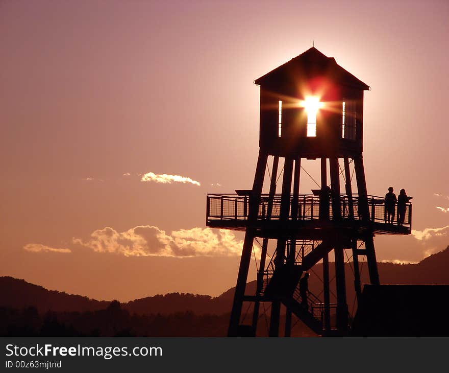 Observation tower in silhouette at sunset on Memphremagog lake, province of Quebec, Canada, with Mont-Orford in background. Observation tower in silhouette at sunset on Memphremagog lake, province of Quebec, Canada, with Mont-Orford in background