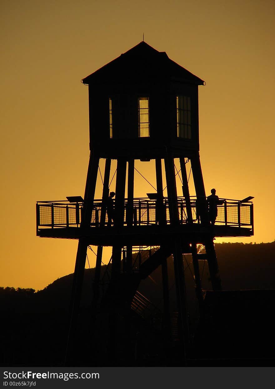 Observation tower in silhouette at sunset on Memphremagog lake in Magog, province of Quebec, Canada, with Mont-Orford in background. Observation tower in silhouette at sunset on Memphremagog lake in Magog, province of Quebec, Canada, with Mont-Orford in background