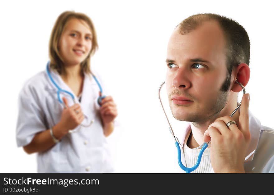 An attractive doctor is listening with a stethoscope. Behind him there is his colleague pretty lady doctor who is smiling. They are wearing white coats. An attractive doctor is listening with a stethoscope. Behind him there is his colleague pretty lady doctor who is smiling. They are wearing white coats.