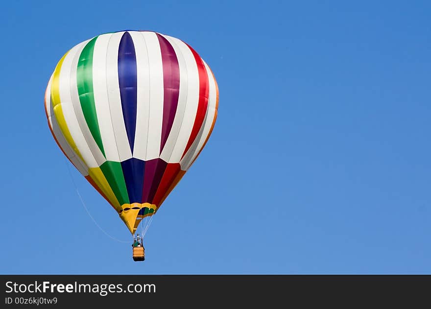 A beautiful hot air balloon floats in the blue sky