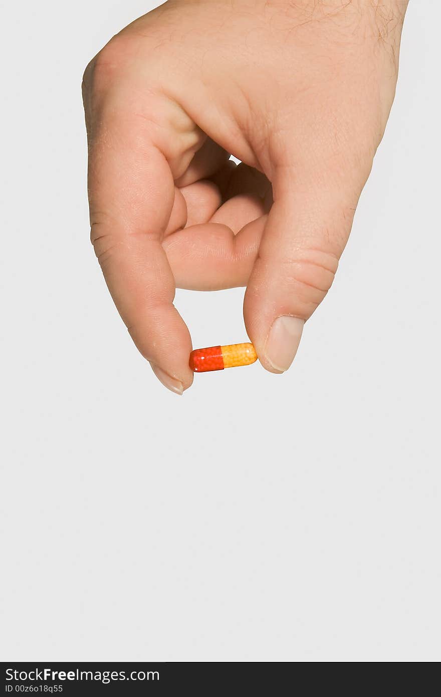 Red and yellow pill held in a hand (clipping path)