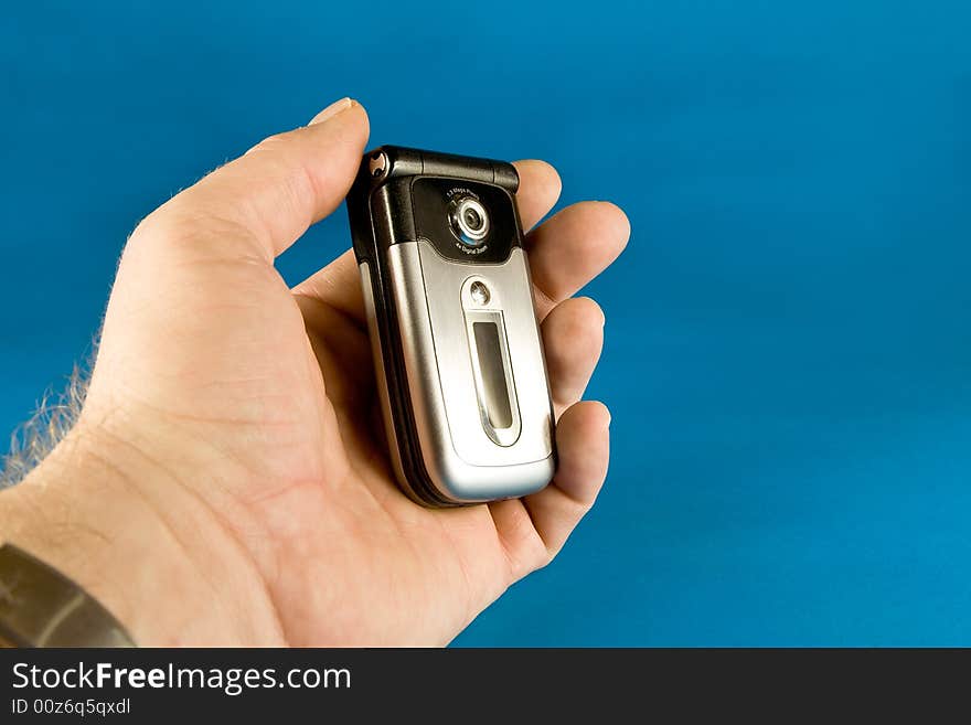 Cell phone held in hand on blue background