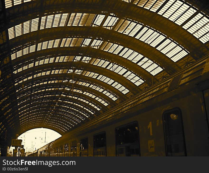 Moving train leaving Italian Train station with vaulted skylight ceiling. Shadows.