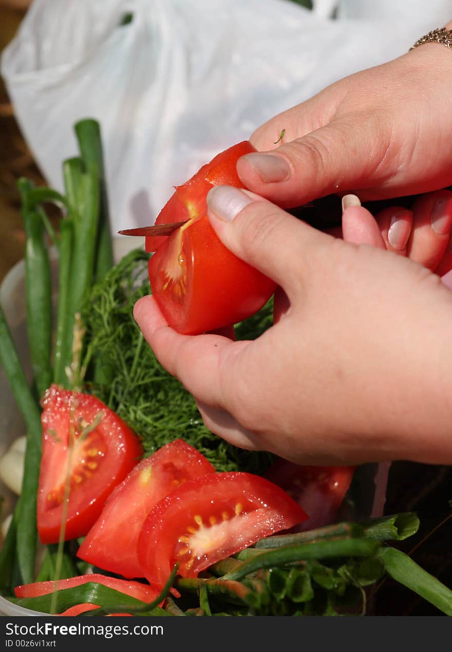 Hands of the girl cut a tomato