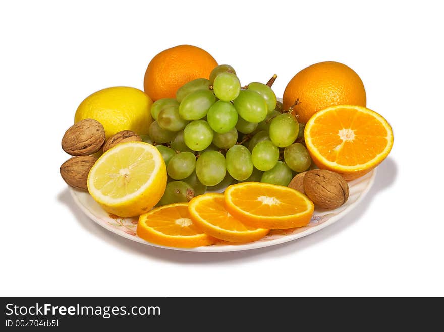 Lemons, sweet oranges, walnut and cluster of vine on a dish. Lemons, sweet oranges, walnut and cluster of vine on a dish