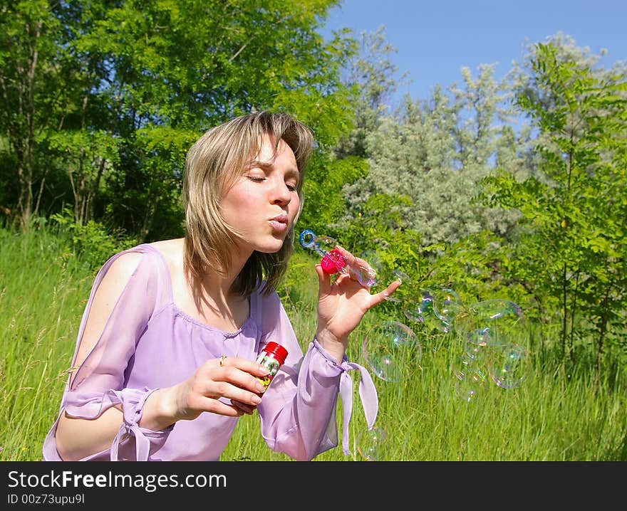 Cute young woman blows a soap bubbles