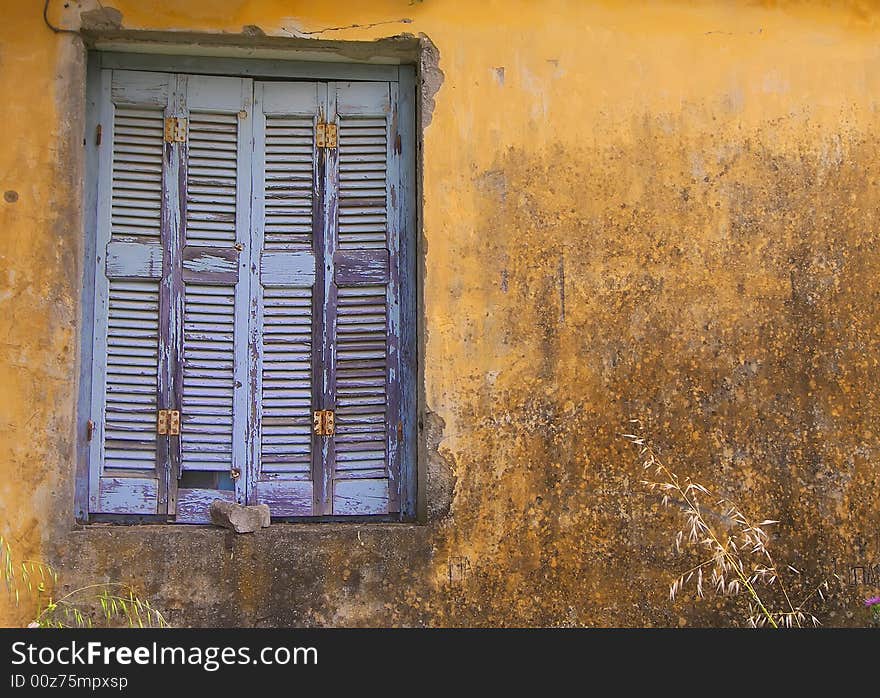 Blue Window Shuttered On Yellow Wall.