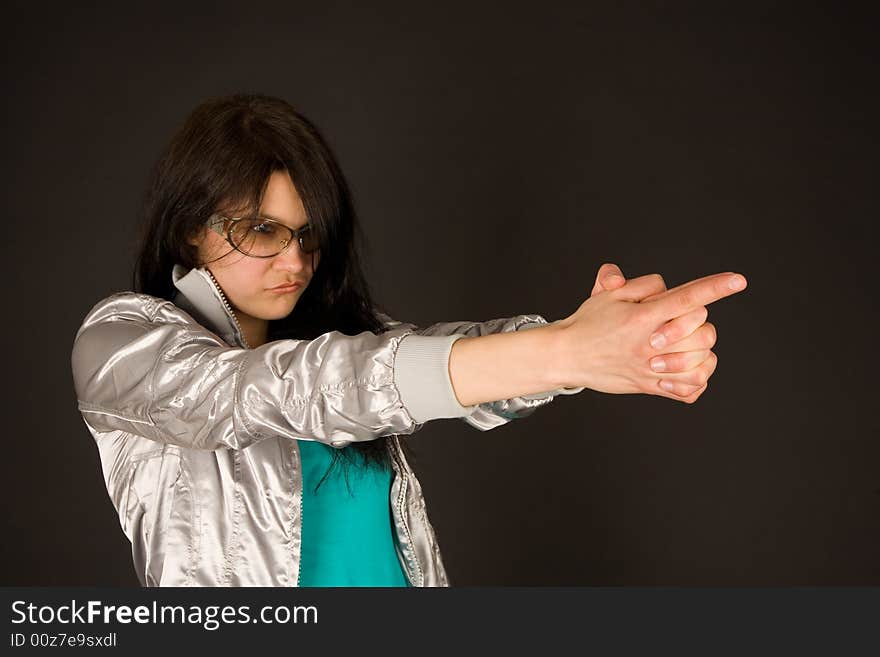 Fashion girl pointing her hands like a gun isolated on black background