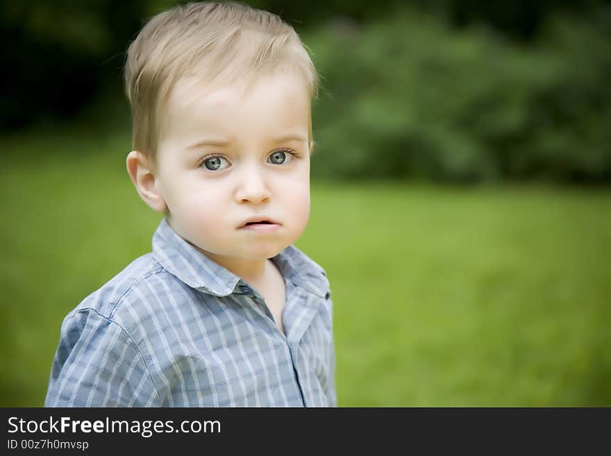 Serious Little Boy On The Nature Background. Serious Little Boy On The Nature Background