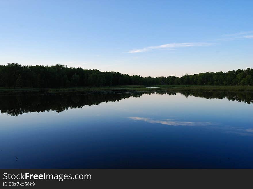 Sky and forest reflected onto lake. Sky and forest reflected onto lake