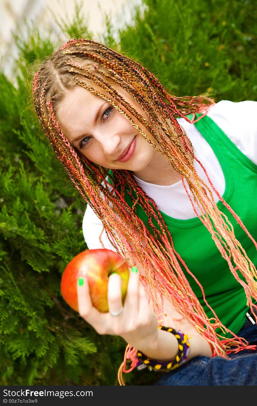 Teenager girl with red apple on the green grass