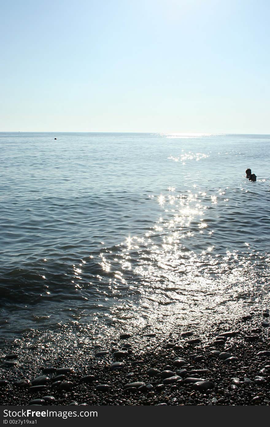 Stony sea beach on background blue sky