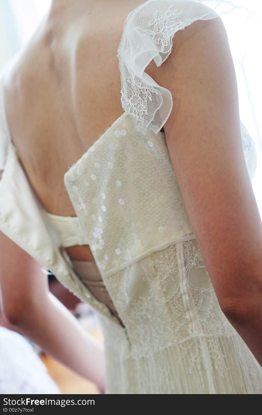 Bride putting on her white wedding dress.