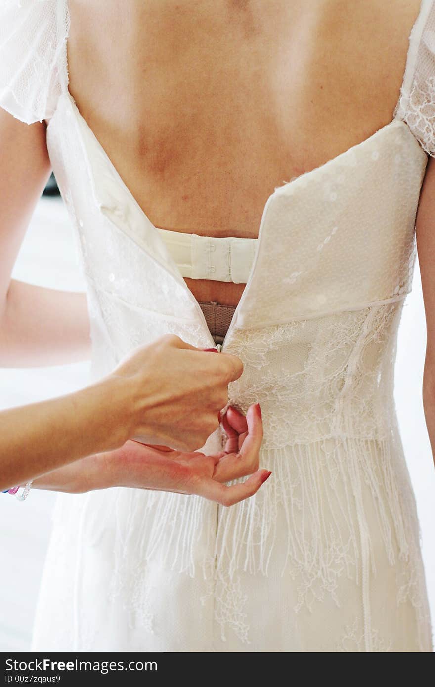 Close-up of a bride having her dress zipped up.