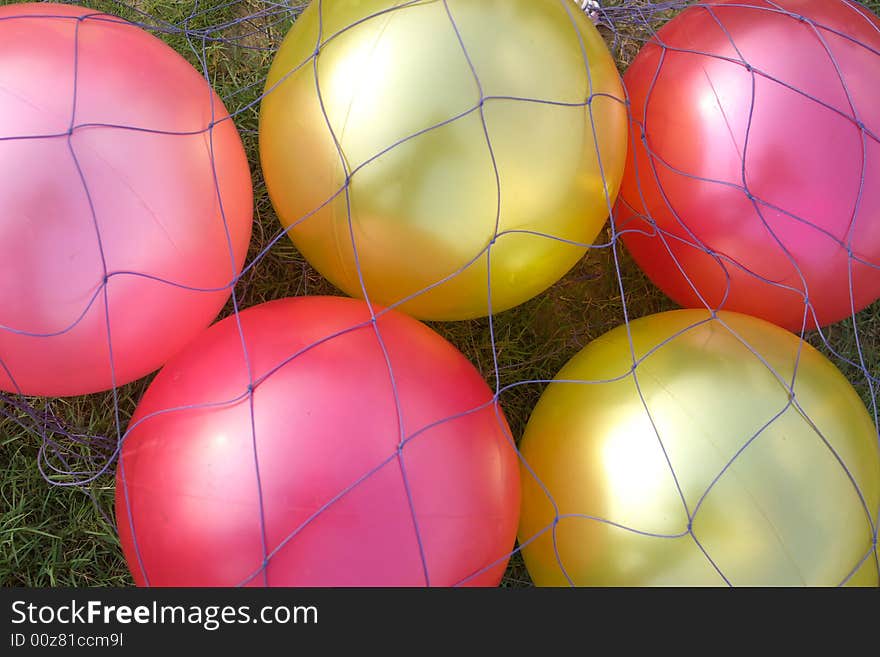 Pure balloons on the grass,they are under the netting.