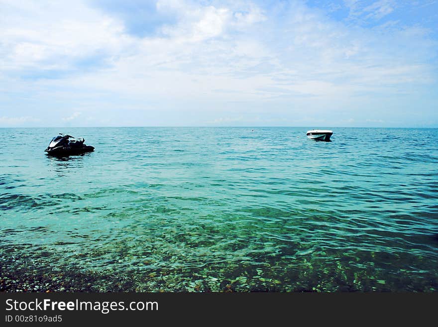 Sea wave and motor boats illuminated year sun on background blue sky