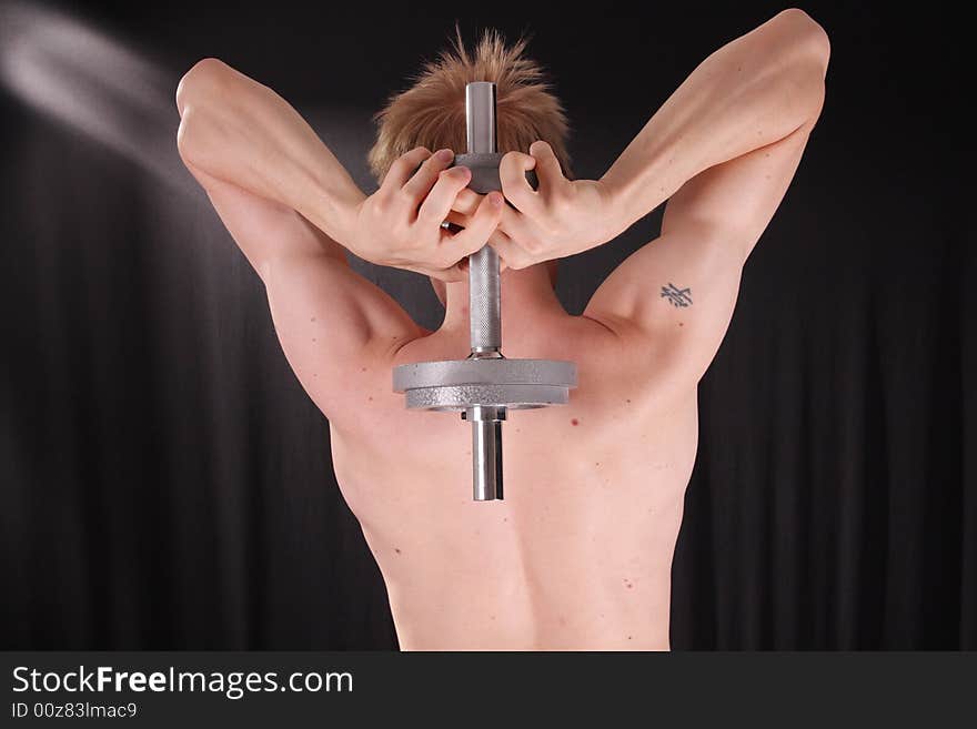 Man training with weight in dramatic studio light