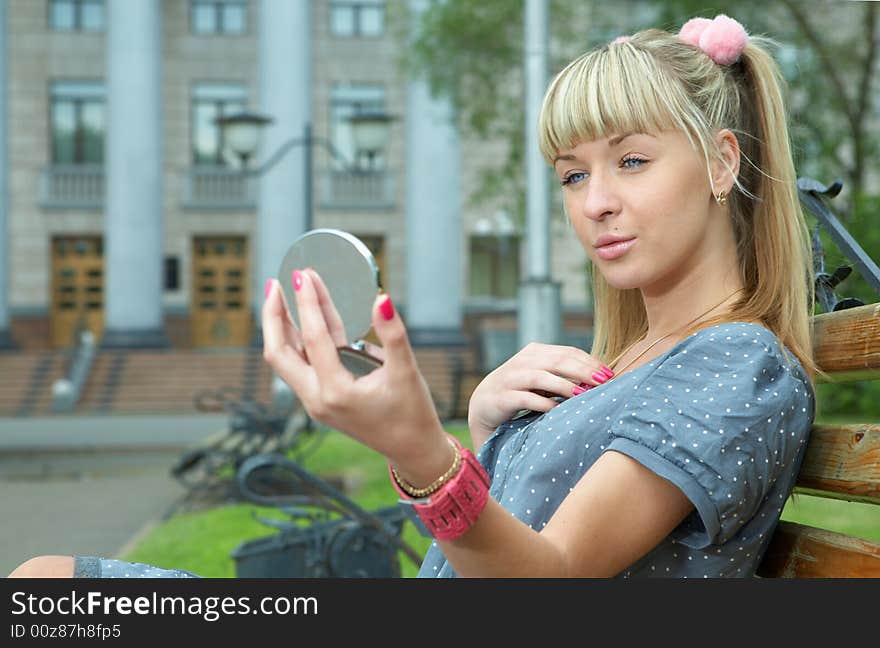 Blonde girl sit on bench and make-up