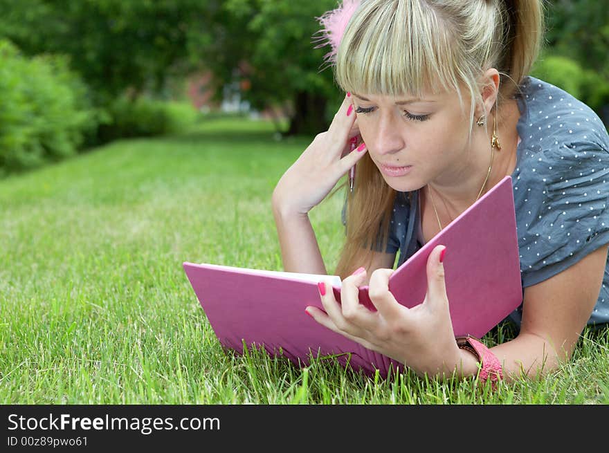 Beauty girl with book on green grass