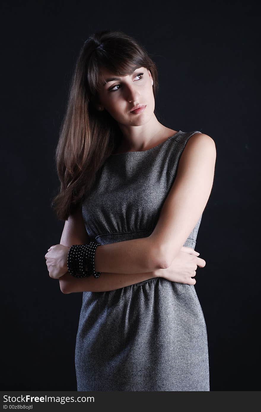 Young beautiful girl in grey clothes on a black background. Young beautiful girl in grey clothes on a black background