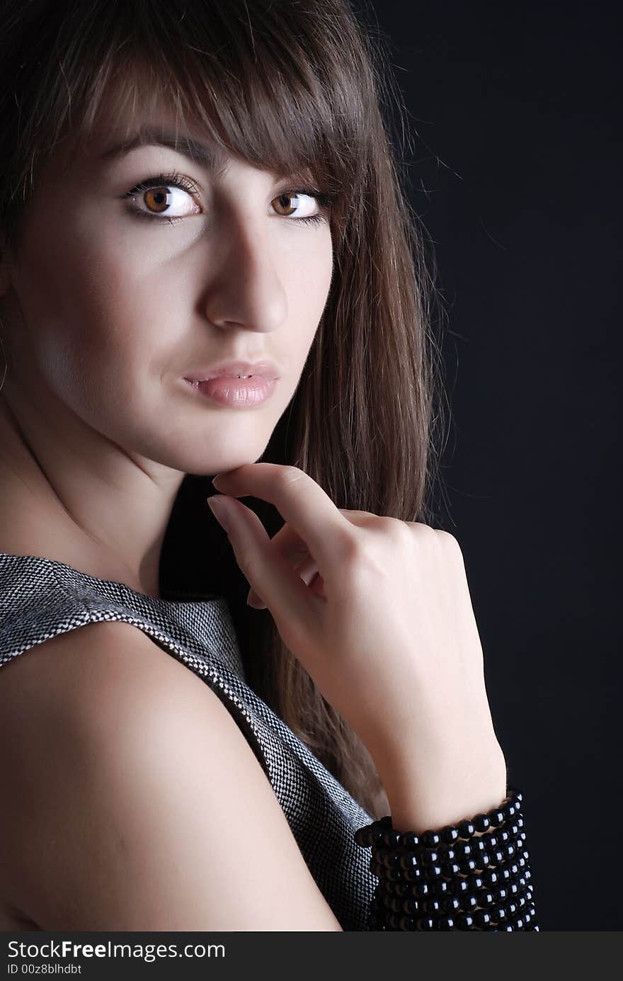 Young beautiful girl in grey clothes on a black background. Young beautiful girl in grey clothes on a black background