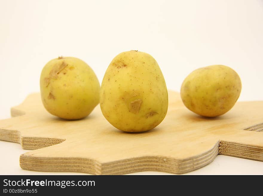 Potatoes on isolated white background over wooden kitchen board