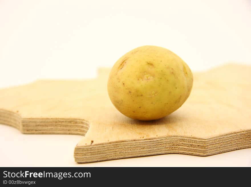 Potato on wooden kitchen board on isolated white background