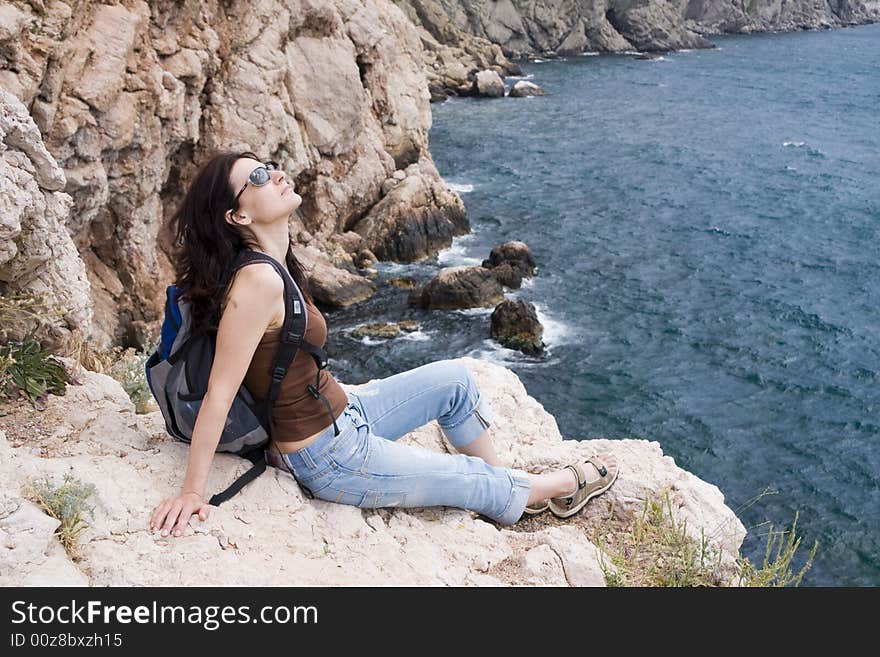 Hiker siting on a stones above the sea coast