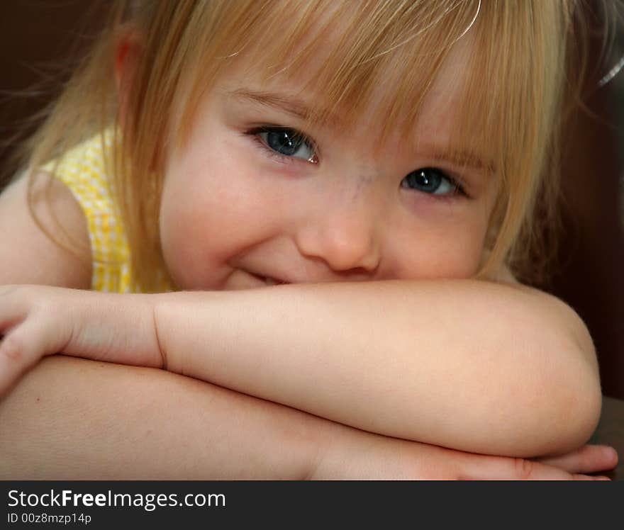 Little girl smiling while resting head on crossed arms. Little girl smiling while resting head on crossed arms