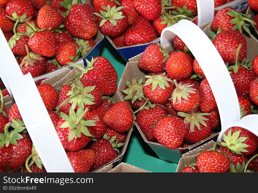 Strawberries are for sale in baskets in a market stall. Strawberries are for sale in baskets in a market stall