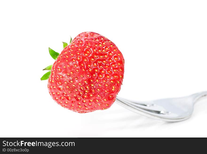 Close up on fresh strawberry on fork on white background