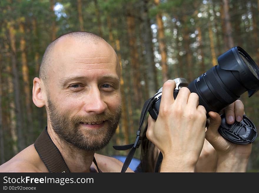 Cheerful smiling photographer in a forest in a sunny day. Close-up. Cheerful smiling photographer in a forest in a sunny day. Close-up