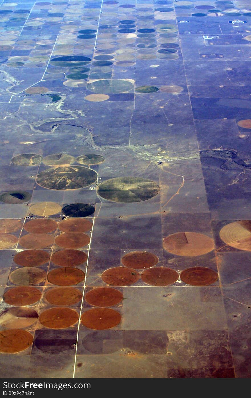 Water problems cause farmers to water in these big circles. There are long poles with sprinklers coming off the bottom of them that water the ground and turn around in a circle. That is the reason for these land formations. The circles are crops, the rest is desert. Water problems cause farmers to water in these big circles. There are long poles with sprinklers coming off the bottom of them that water the ground and turn around in a circle. That is the reason for these land formations. The circles are crops, the rest is desert.