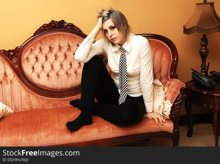 An pretty young girl in a white blouse and black and white tie sitting on a pink
sofa and look very down. An pretty young girl in a white blouse and black and white tie sitting on a pink
sofa and look very down.