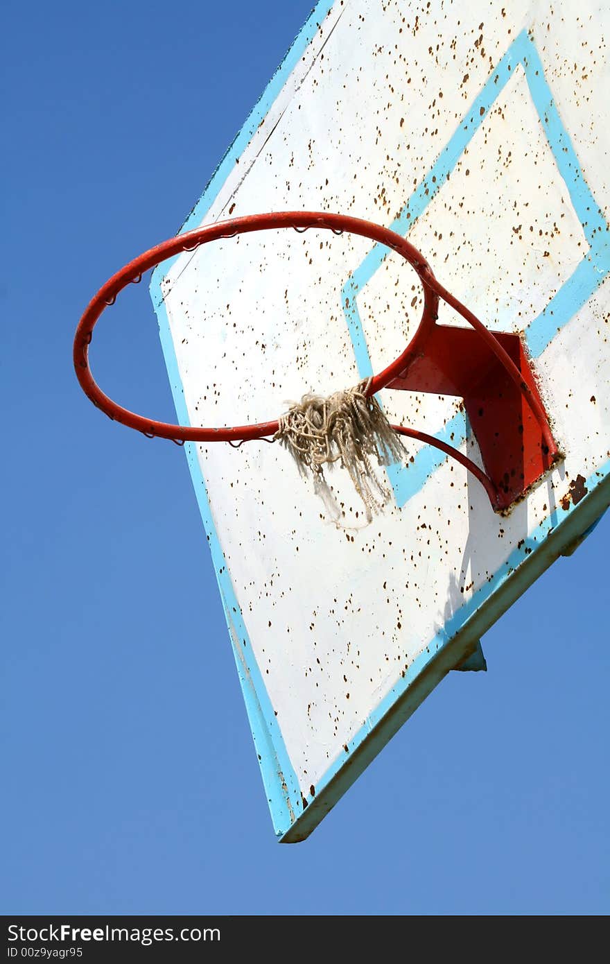 Old basketball hoop on clear blue sky.