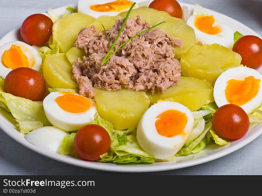 Salad with boiled potato, fish, egg, tomato and lettuce.