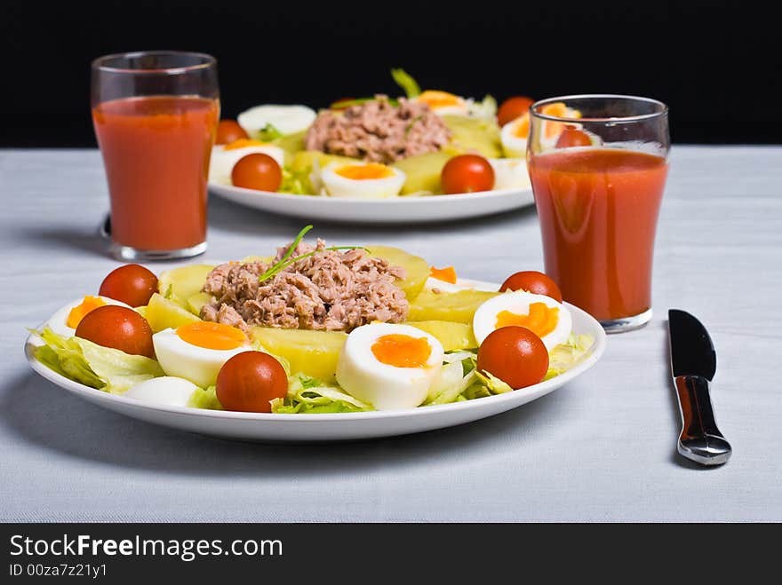 Salad with boiled potato, fish, egg, tomato and lettuce.