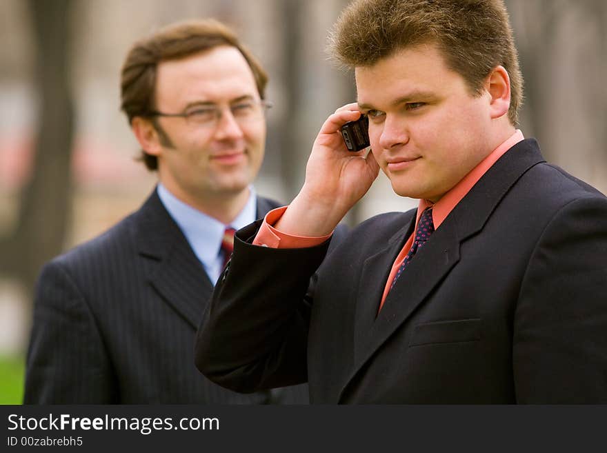 Two businessmen, one making a call