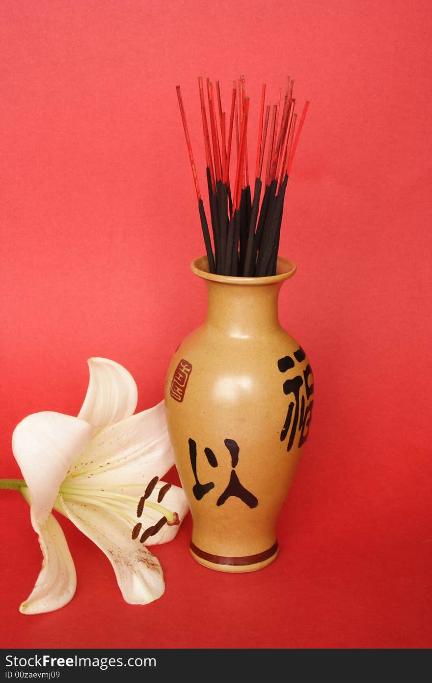 Incense sticks in a Chinese jug and Madonna lily. Incense sticks in a Chinese jug and Madonna lily