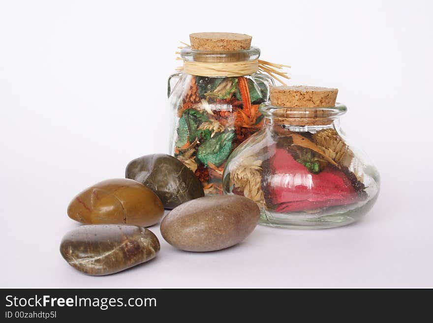 Bottles of scented flowers and pebbles isolated. Bottles of scented flowers and pebbles isolated