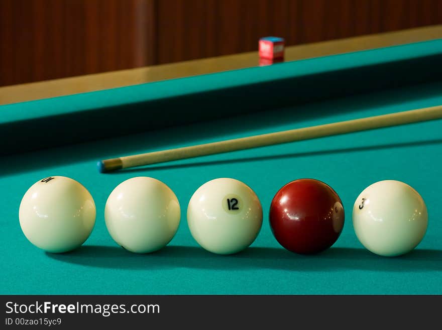 Four white billiard balls and a red ball with a cue at the green table. Four white billiard balls and a red ball with a cue at the green table