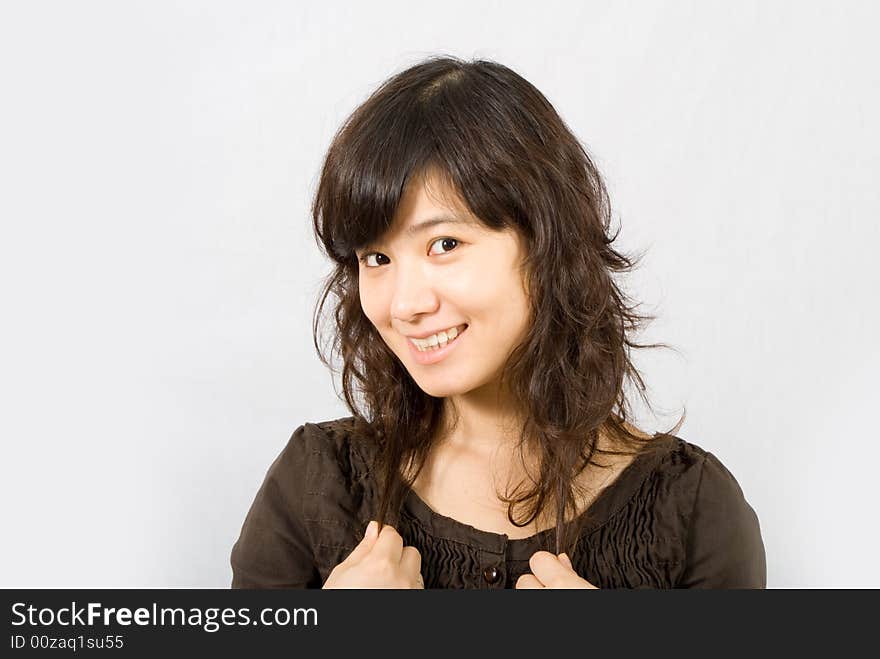 A cute asian girl wears a brown skirt with both of her hands grabbing her curved hair. A cute asian girl wears a brown skirt with both of her hands grabbing her curved hair.