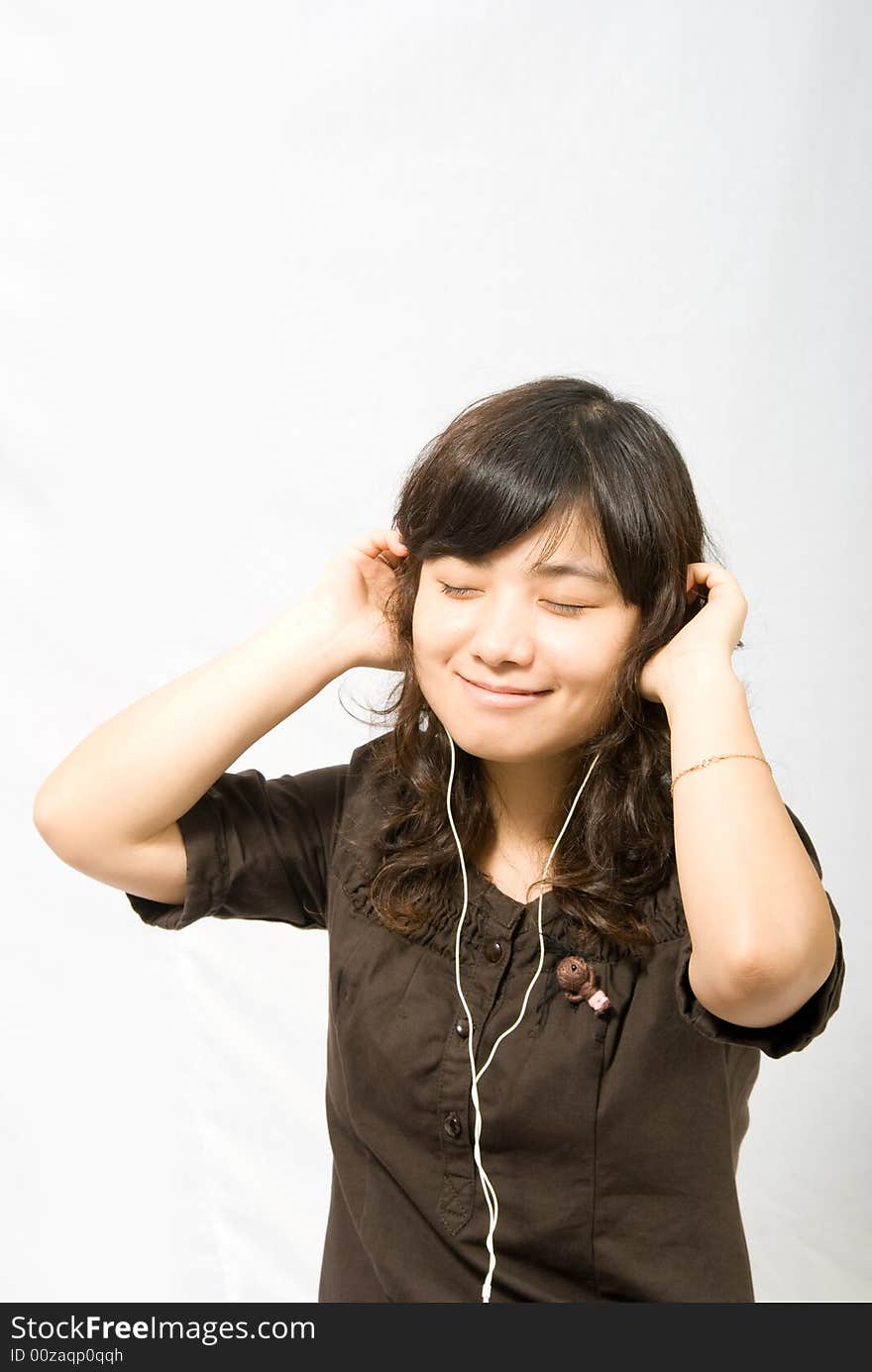 A young lady is enjoying the music through the white earphone. A young lady is enjoying the music through the white earphone