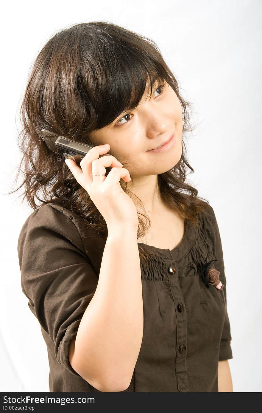 A asian female adolescent in brown skirt with light brown curved hair is calling her boyfriend with a slide hand phone. A asian female adolescent in brown skirt with light brown curved hair is calling her boyfriend with a slide hand phone.