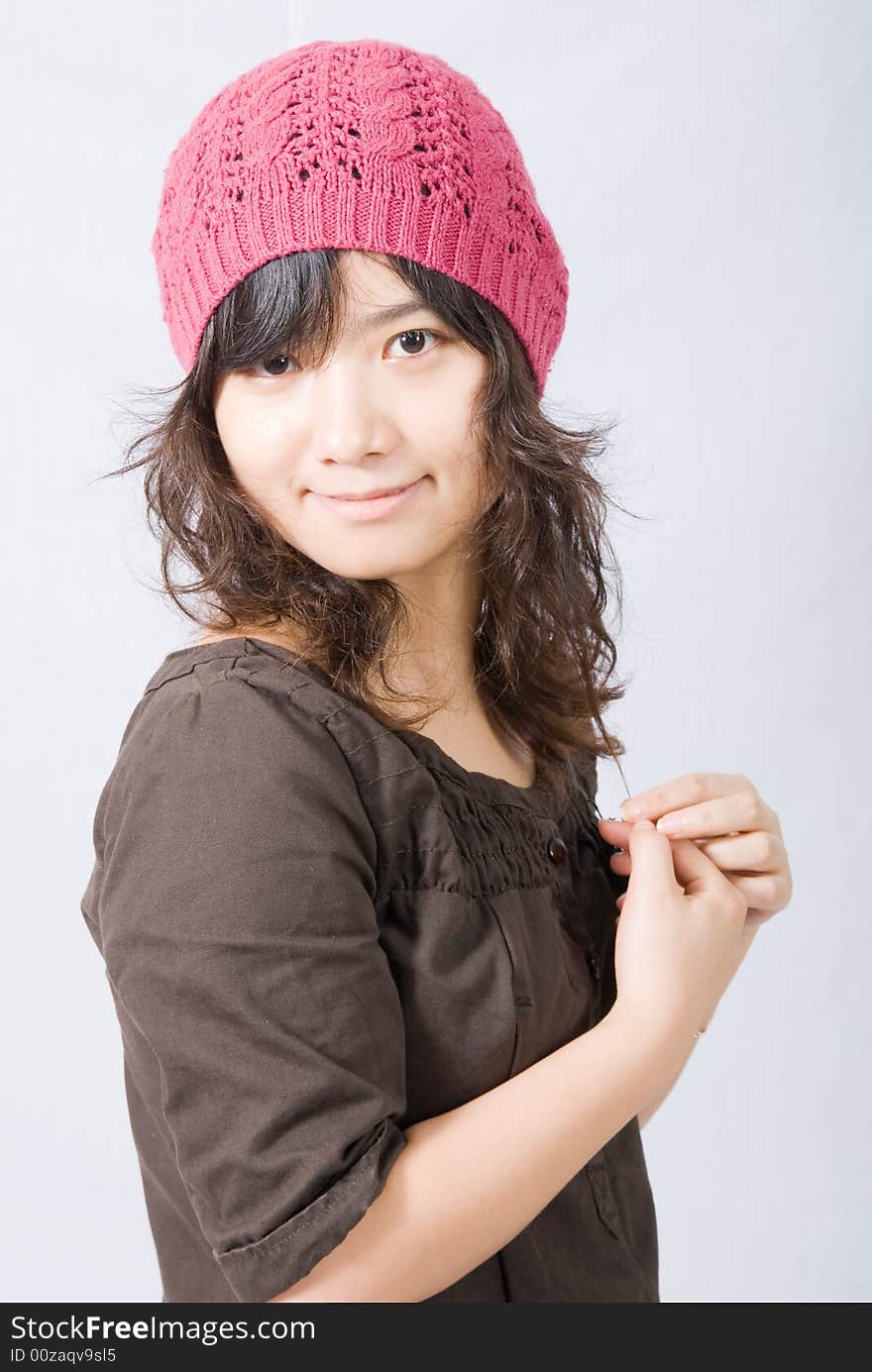 A cute asian girl wears a pink and red hat with her hands on the front. A cute asian girl wears a pink and red hat with her hands on the front